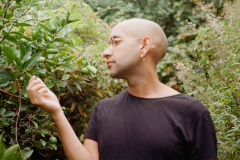 Anuraag-Bhatia-Photo-by-Hannah-Alexander-an-image-of-a-person-with-in-glasses-and-with-an-earring-looking-sideways-to-surrounded-by-trees