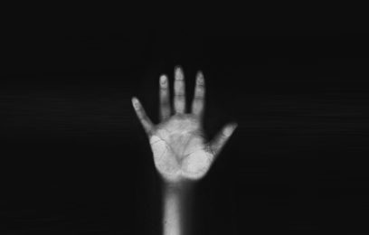 A black and white greyscale, scan of a hand against glass with deep black background