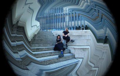 two-people-in-black-sit-on-concrete-steps-with-jagged-architectural-features-behind-them-the-image-has-liquid-and-distorted-edges